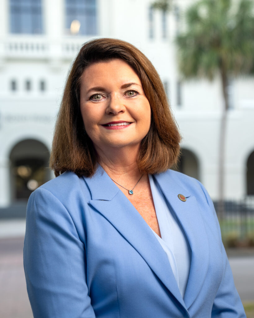 Professional headshot of Allison Love in a light blue blazer standing outdoors in front of The Citadel.