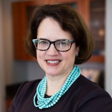 Headshot of Laurie Champion smiling, wearing glasses and a turquoise necklace.