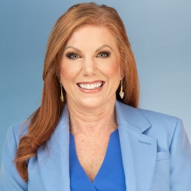 Headshot of Marva Bailer smiling, wearing a blue blazer and earrings against a blue background.