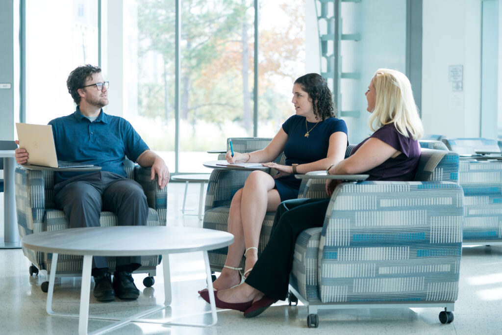 Three people seated together in a campus lounge during a discussion.