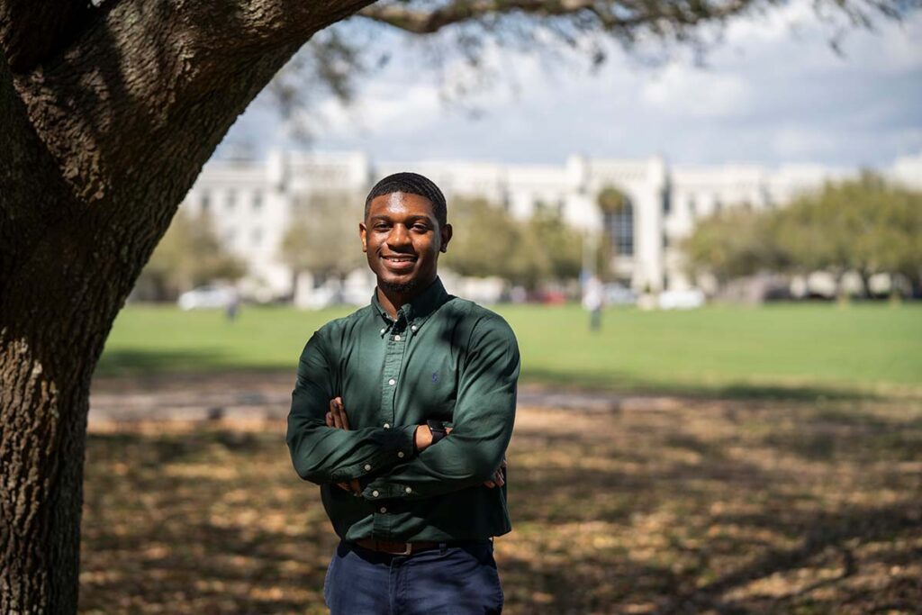 Smiling man standing outdoors beneath a large tree on The Citadel campus.