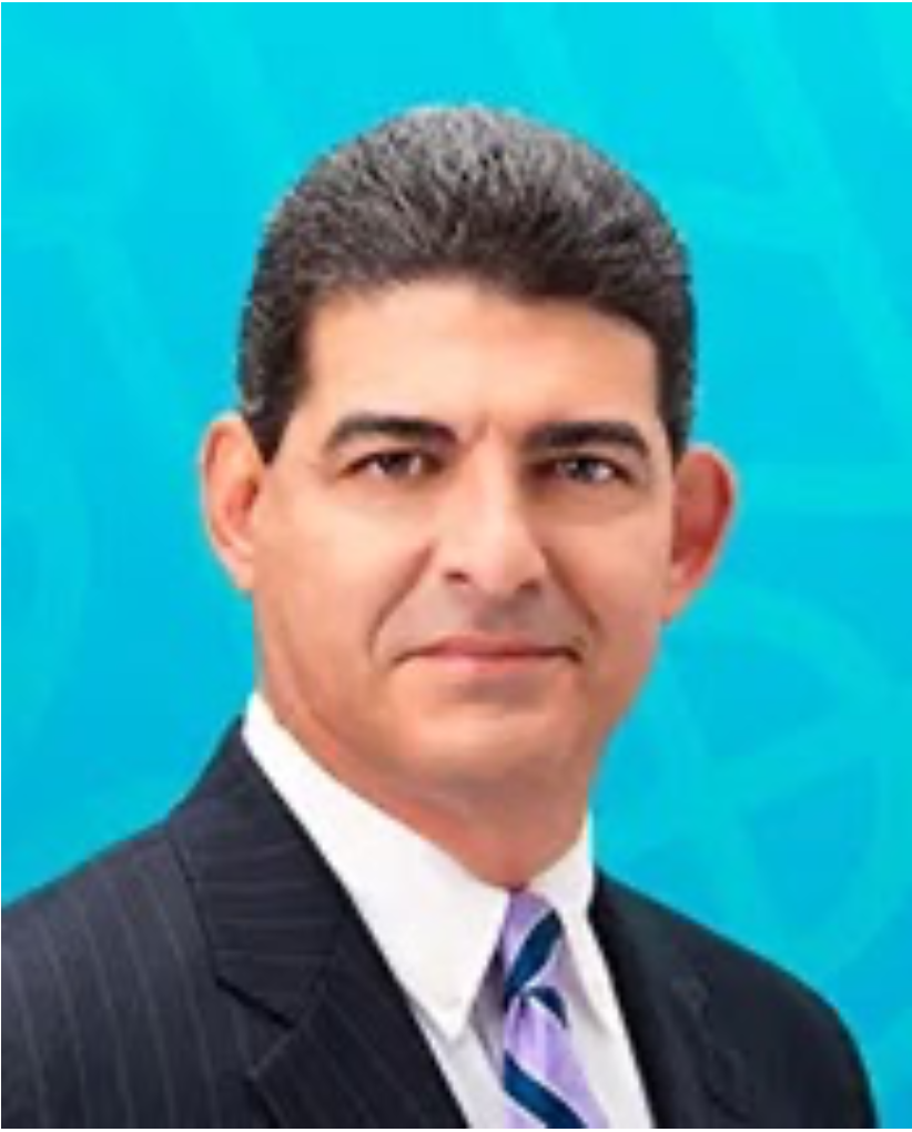 Portrait of Hernan Pena in a dark suit and striped tie, facing the camera against a blue background.