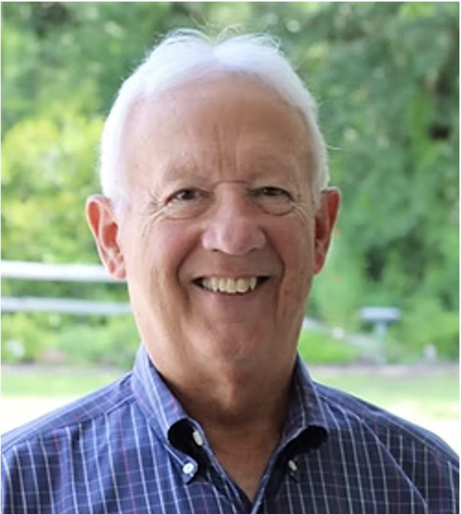 Headshot of Johnston Peeples, smiling and wearing a blue checkered shirt, standing outdoors.