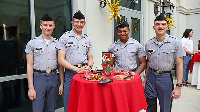 four men standing around a table with food