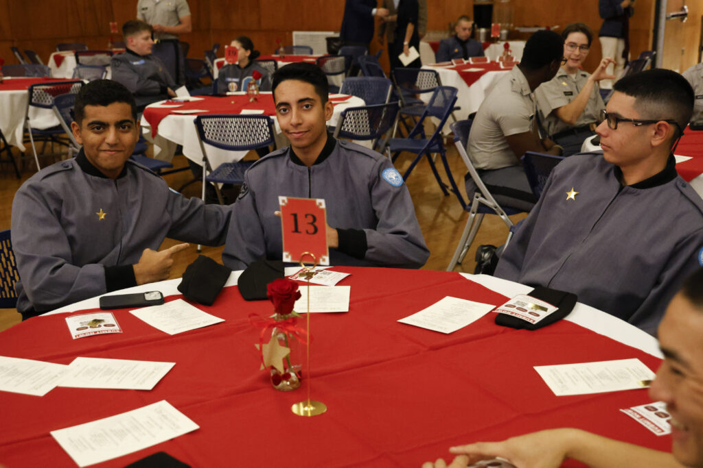 Cadets smiling for a photo at their table.