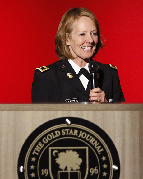 Provost Dr. Sally Selden standing in front of a bright red background