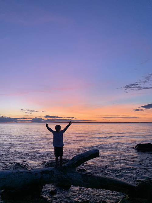 Photograph of a child standing on rock in sunset on Fishers Island.