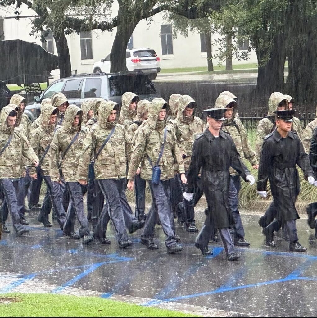 Citadel cadets carrying water bottles while marching in the rain during Challenge Week.