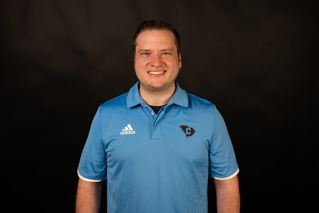 Man wearing a blue Citadel polo poses against a black background.