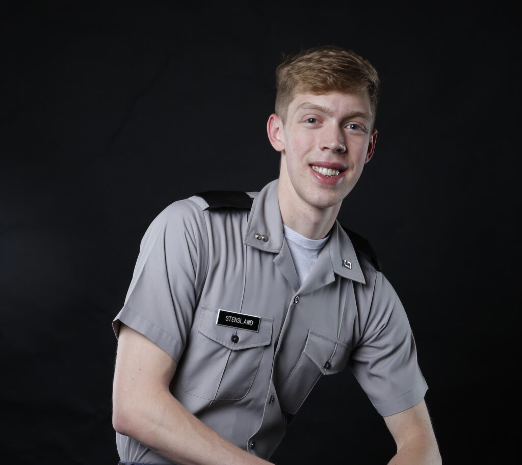 Smiling Citadel cadet Stensland in a gray uniform posed against a black background.