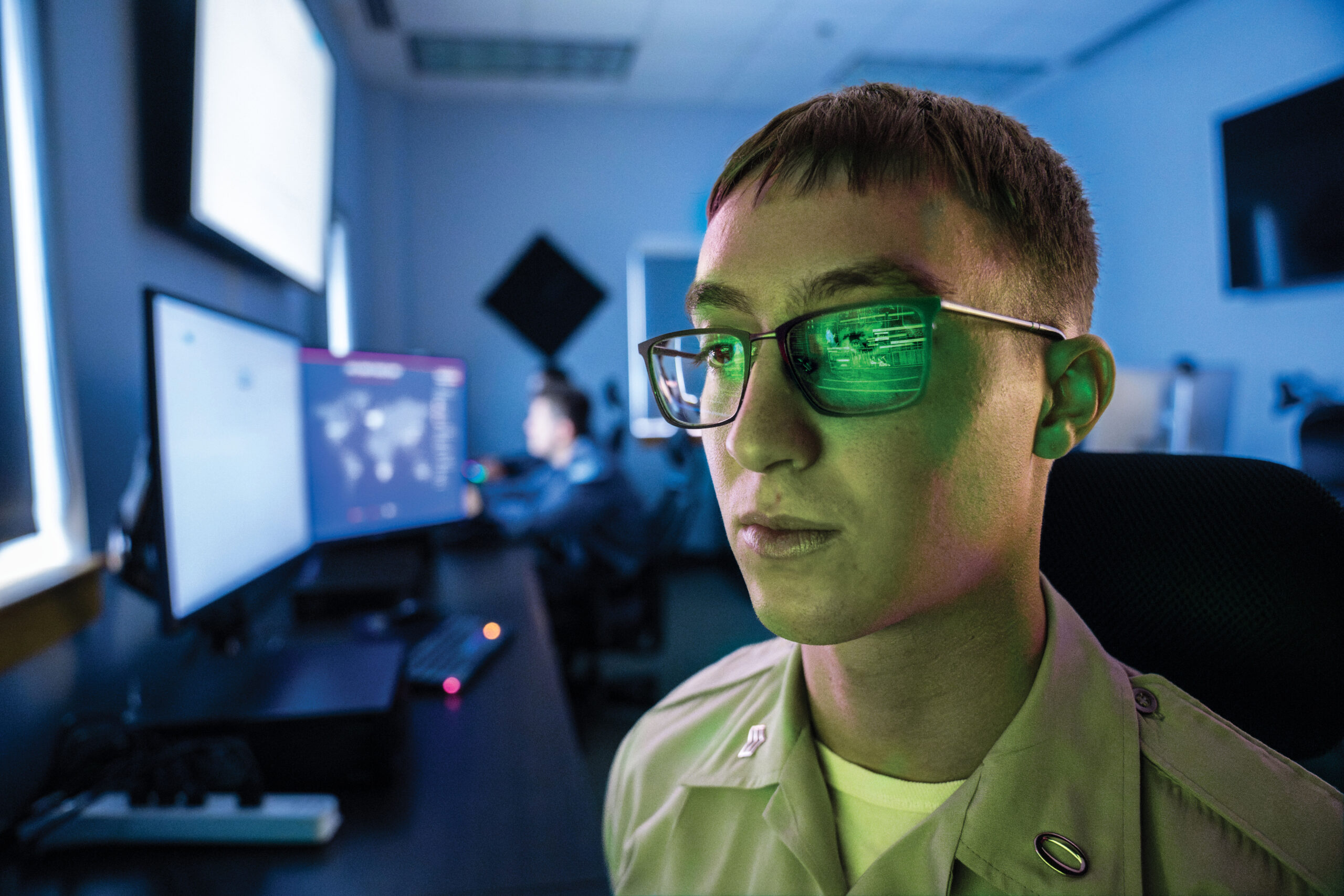 Cadet works at a computer in The Citadel's cyber lab, with code reflected in their glasses.