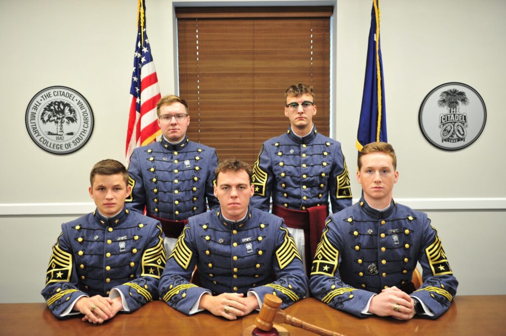 Five Citadel cadets in dress uniforms pose as Honor Committee officers, with a gavel on the table in front of them.
