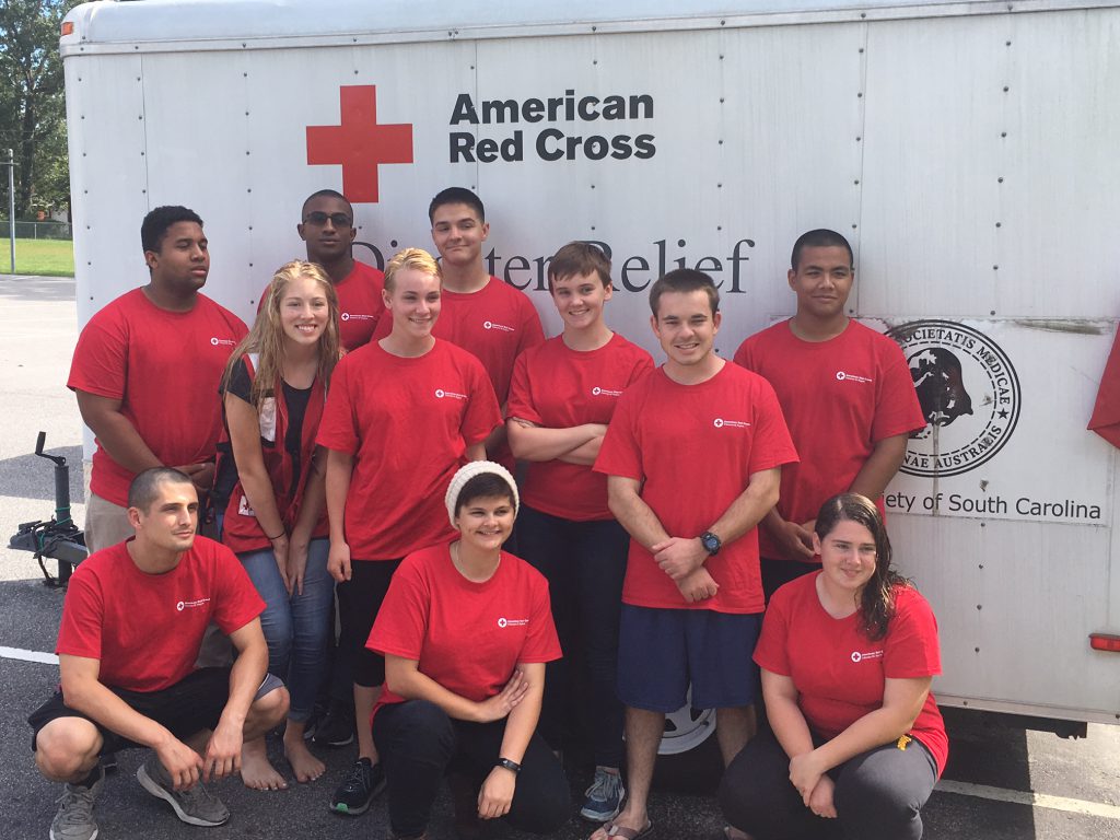 Group of volunteers poses in front of an American Red Cross disaster relief trailer.