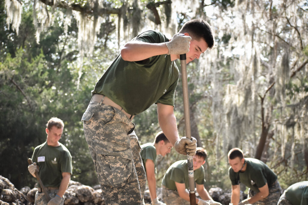 Citadel cadets work with shovels during an outdoor community service project.