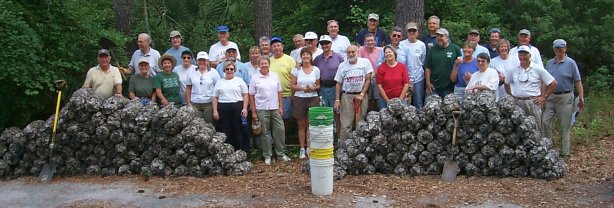 Group of volunteers posing outdoors behind large piles