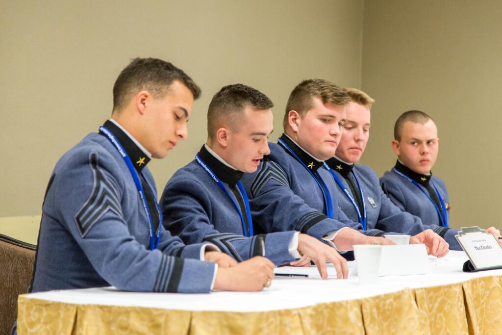 Citadel cadets in dress uniforms participate in a panel discussion at a leadership conference.