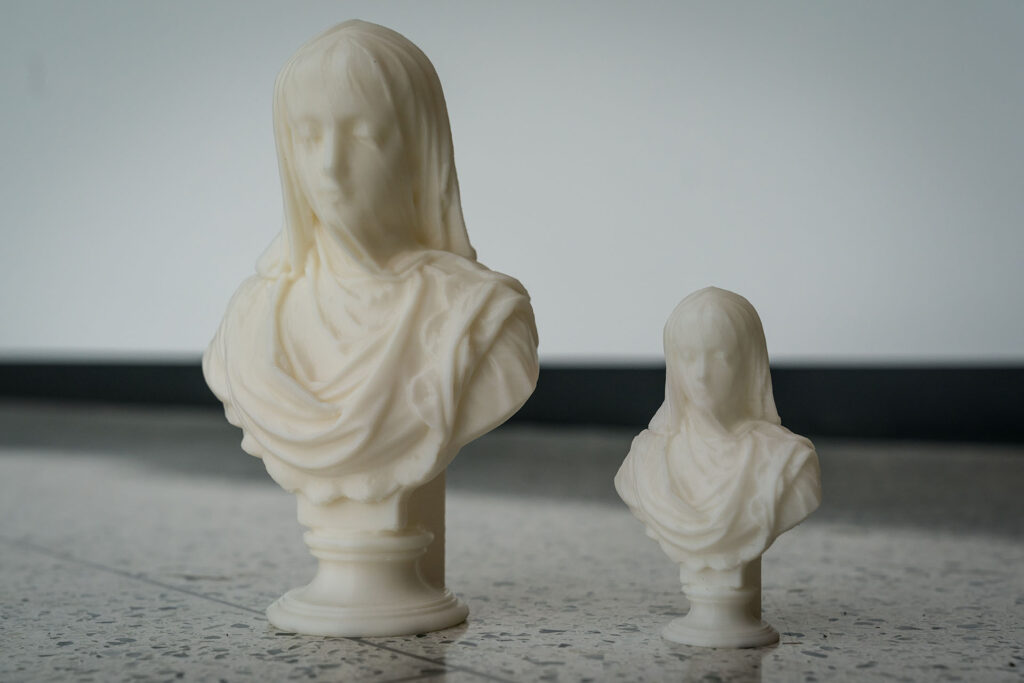 Two white sculpted busts displayed side by side on a tabletop.