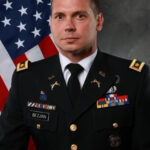 Professional portrait of Business Professor James Bezjian, Ph.D., wearing his dress military uniform with the U.S. flag in the background.