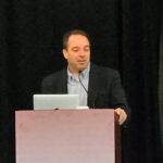 Mark McKinney, Ph.D., speaks at a podium during the Electrical and Computer Engineering Department Heads Association annual conference, with attendees seated in the foreground.