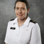 Professional portrait of Amy Emm, Ph.D., on a gray background.