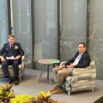 Baker School of Business Dean Michael R. Weeks, in uniform, sits onstage in an armchair as he facilitates a discussion with Isaac Morton, founder and CEO of Smithey Ironware Company, who is seated opposite him.