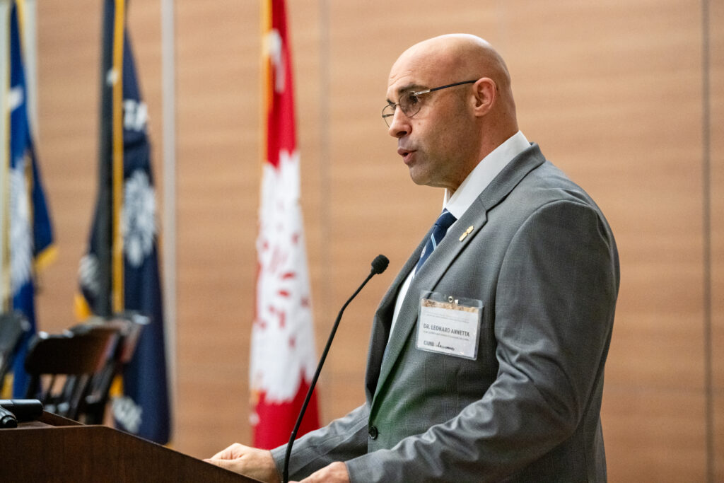 Behind a podium Zucker Family School of Education Dean Leonard Annetta welcomes guests to the Camo to Classroom initiative.