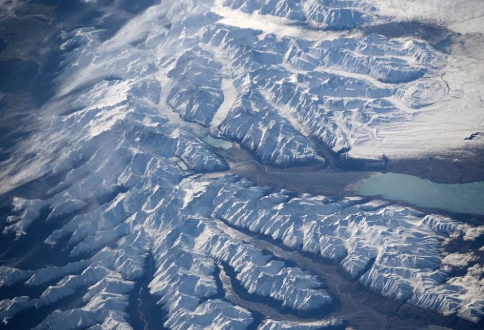 Aerial view from space of snow-covered mountains, glaciers and turquoise glacial lakes.