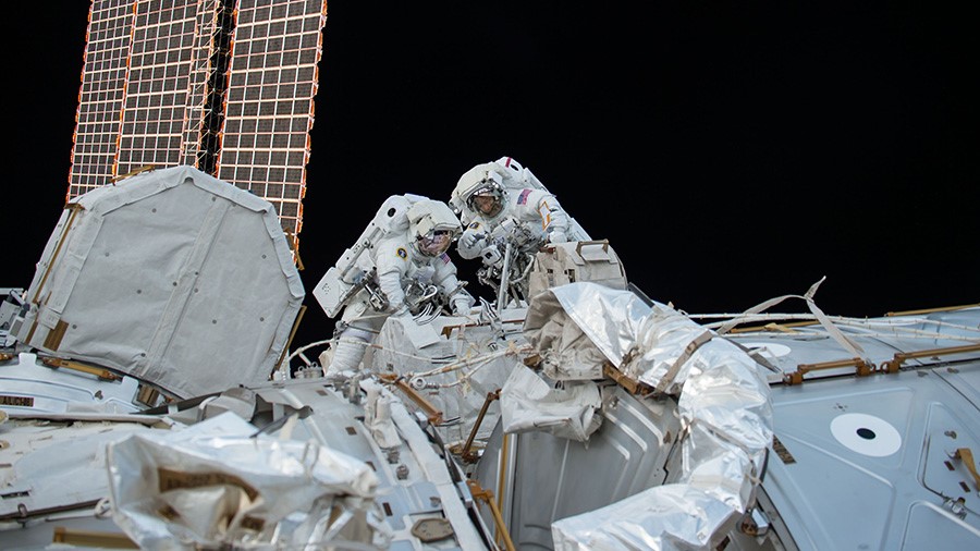Two astronauts perform a spacewalk outside the International Space Station.