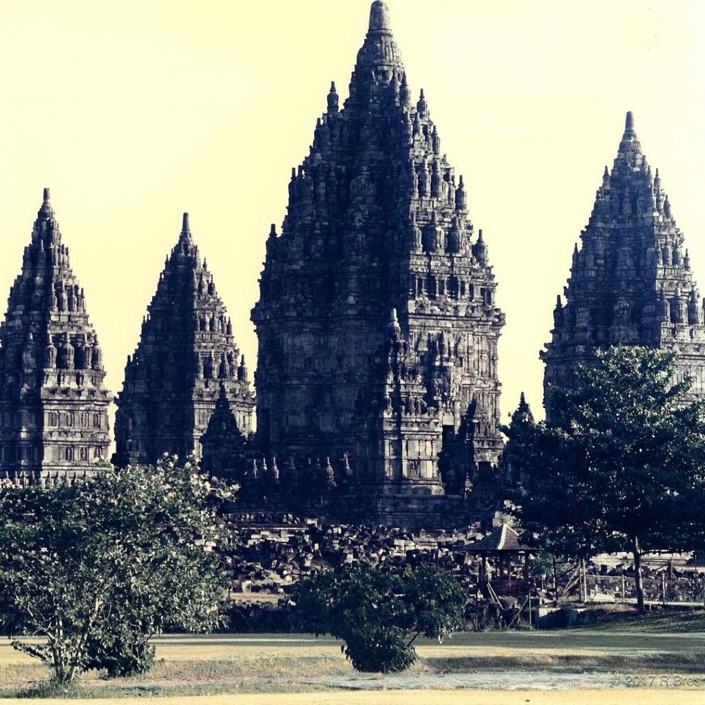 Ancient stone temple towers rise above trees and landscaped grounds.