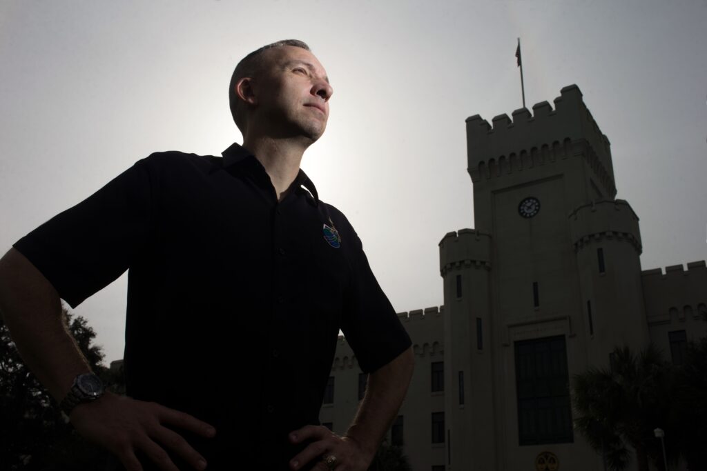 Man stands with his hands on his hips in front of The Citadel’s Padgett-Thomas Barracks clock tower.