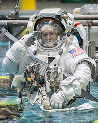 Astronaut in a spacesuit participates in underwater training while giving a salute.