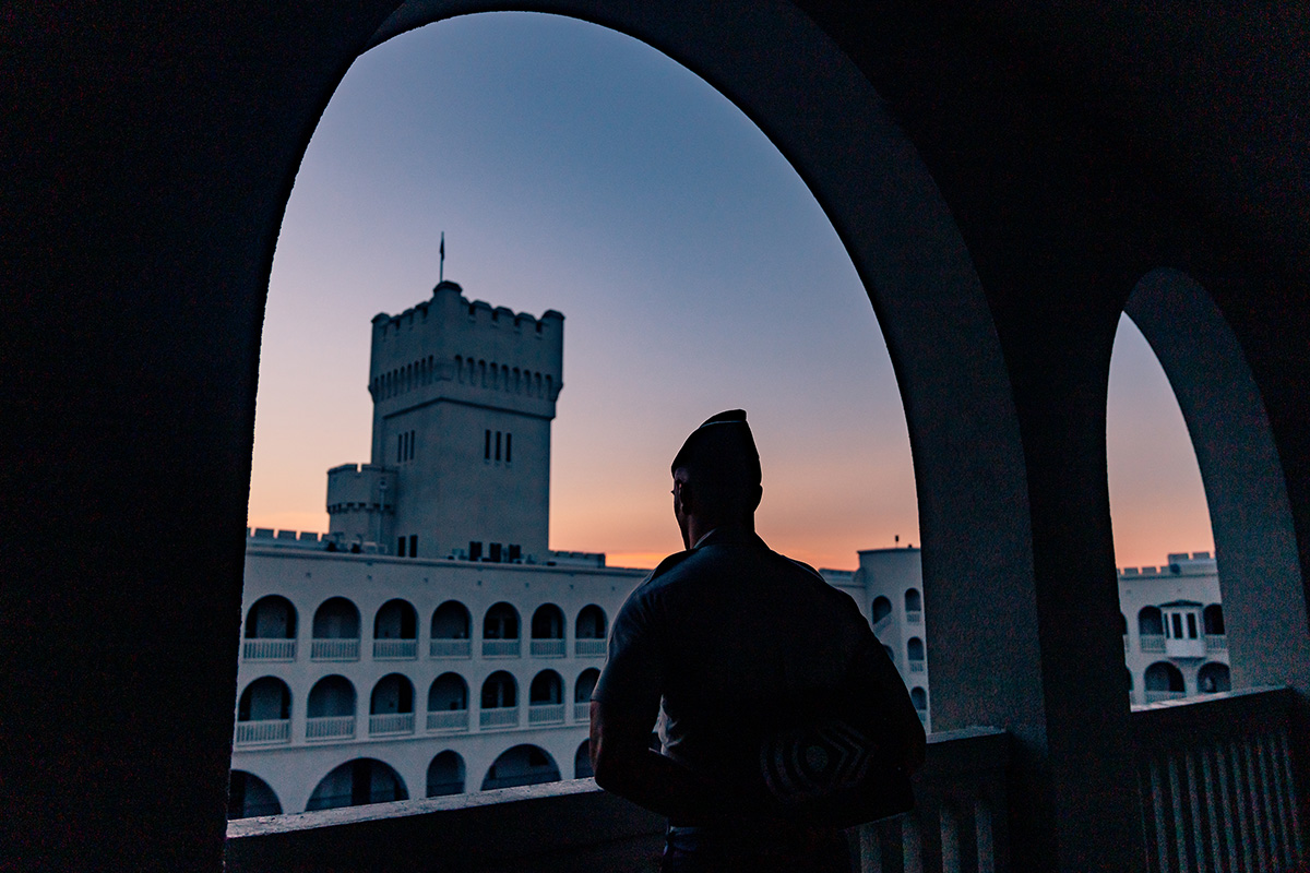 Cadet standing on a balcony at sunset, overlooking The Citadel’s tower and barracks.